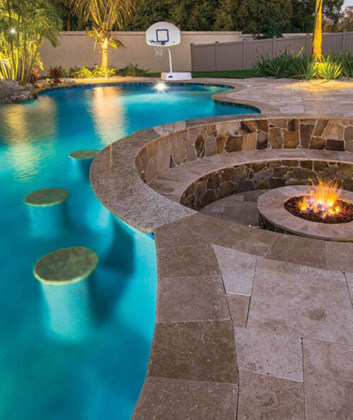 Travertine tiles around a fire pit and pool.