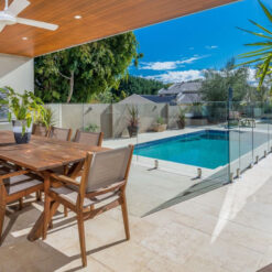 Ivory travertine tiles around a pool with an outdoor table.