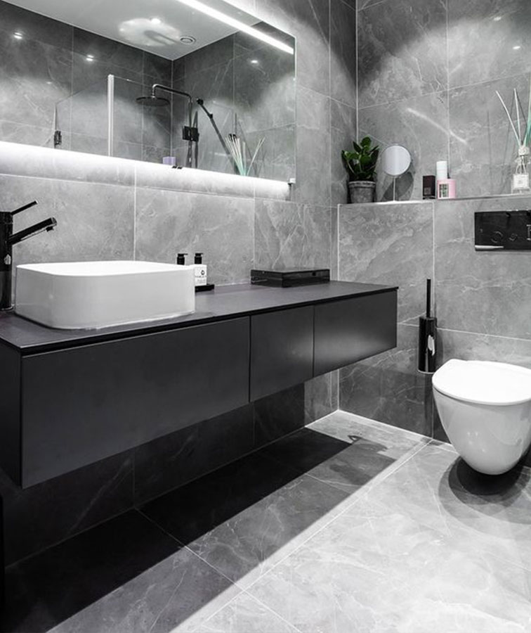Grey marble bathroom tiles, next to a black sink and toilet.