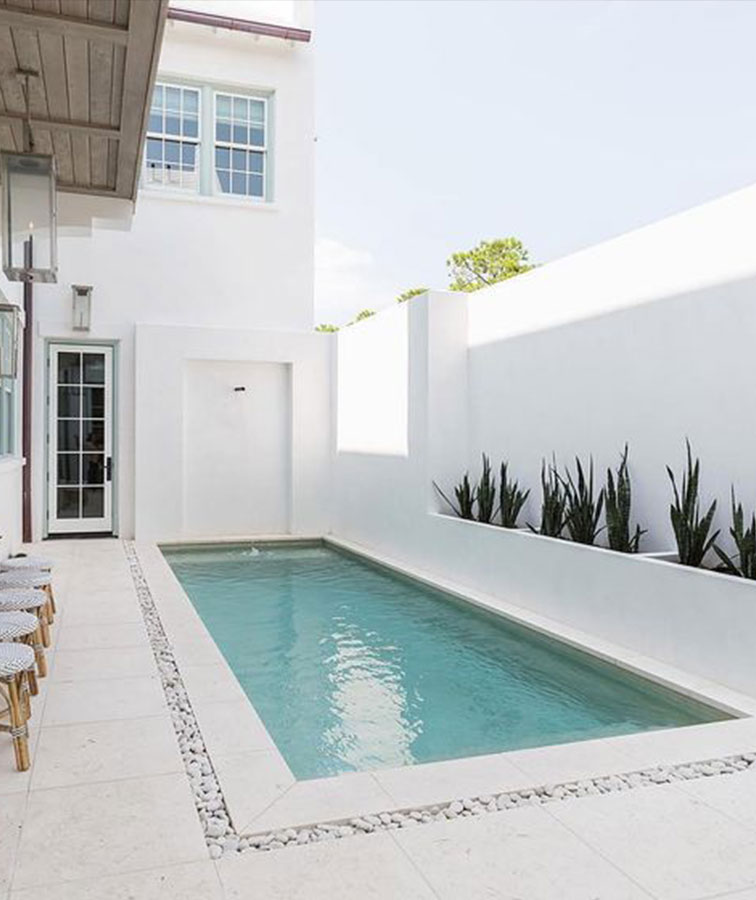 White travertine tiles and pool coping around a pool area.